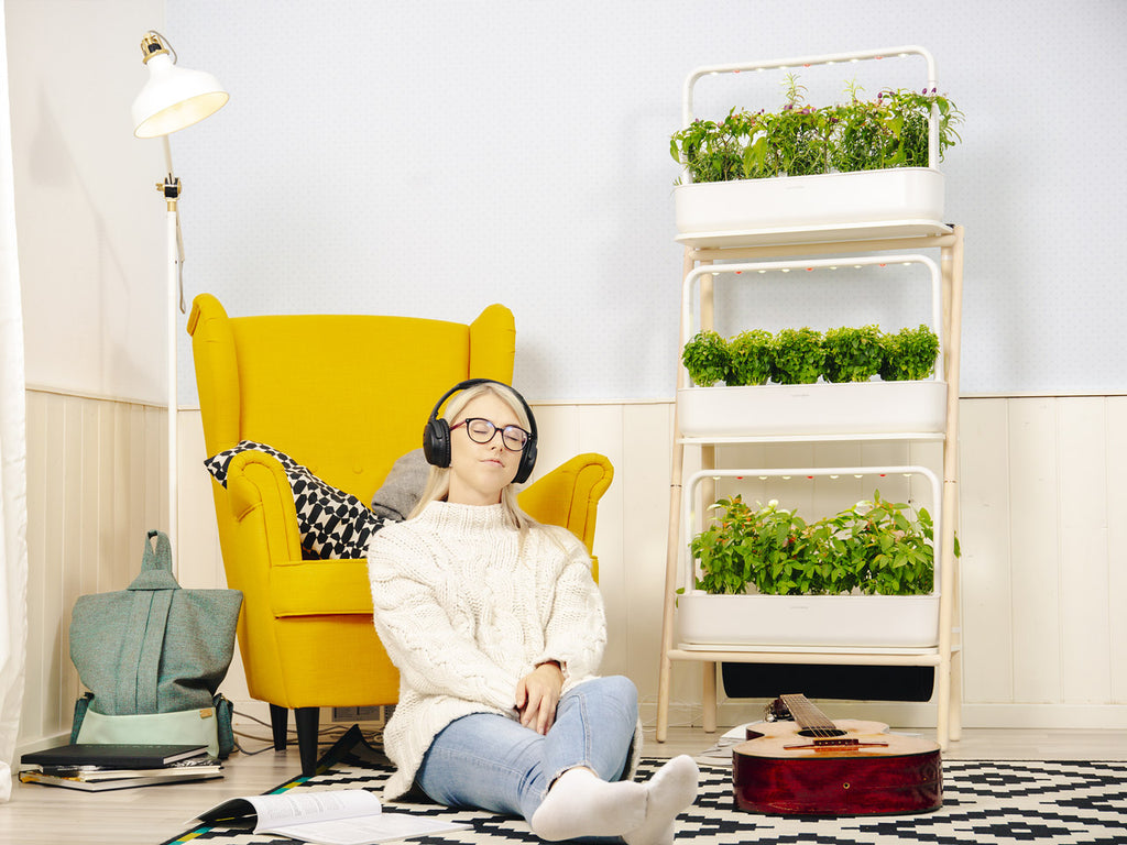 Girl relaxing with headphones in front of the Click and Grow 27.