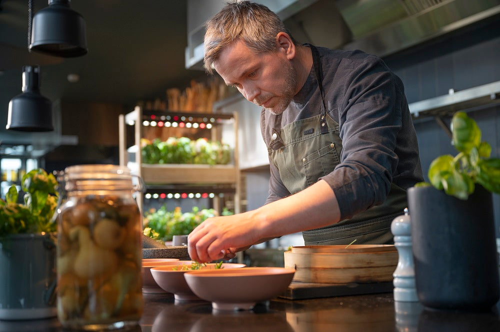 Chef preparing a meal with the Click and Grow 25 in the background.