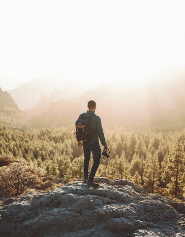 Man holding a camera and observing the horizon.