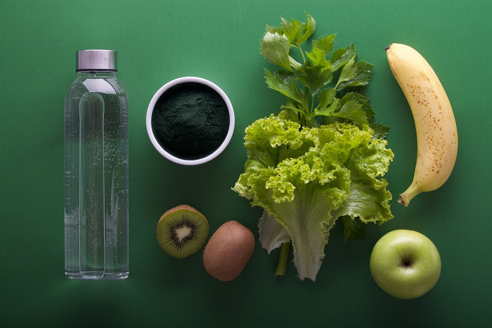 Healthy food and water against a green backdrop.