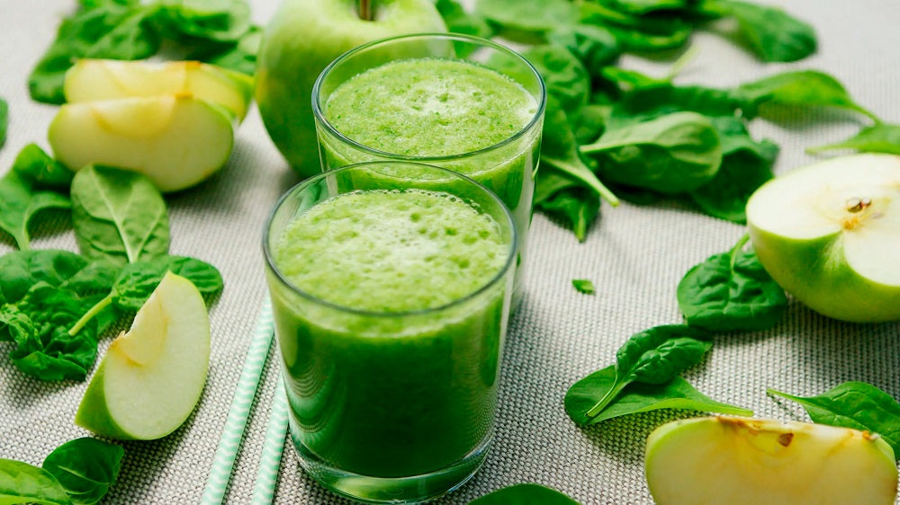 Glasses of green smoothies on a table.