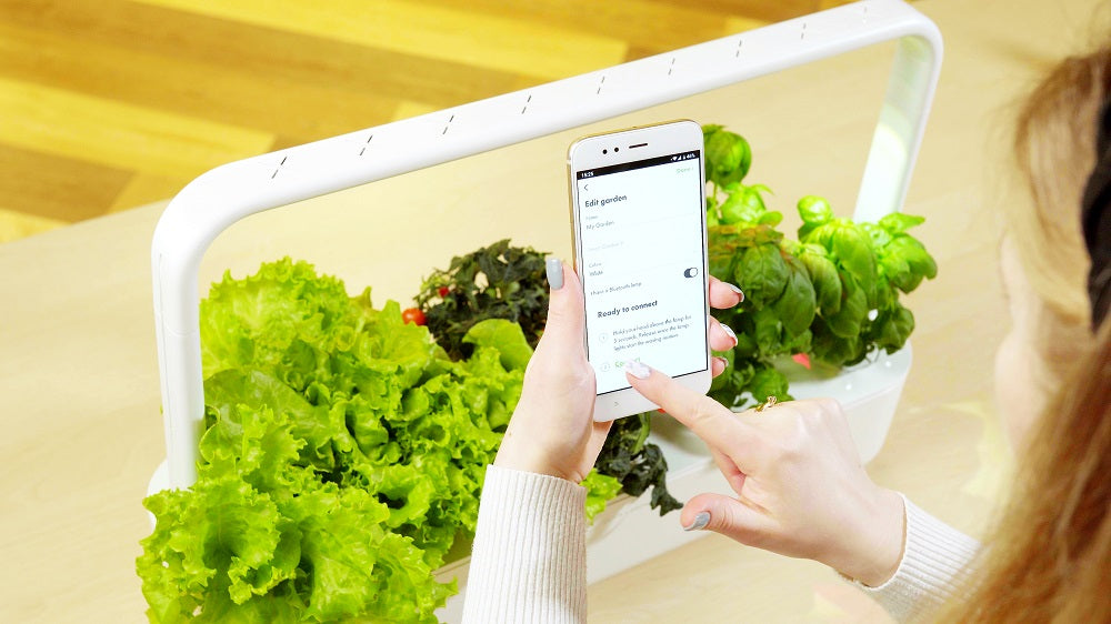 Woman operating the Smart Garden 9 PRO using the Click and Grow mobile app.