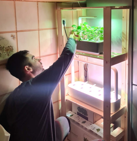 Man tending to plants in the Click and Grow Smart Garden 3.