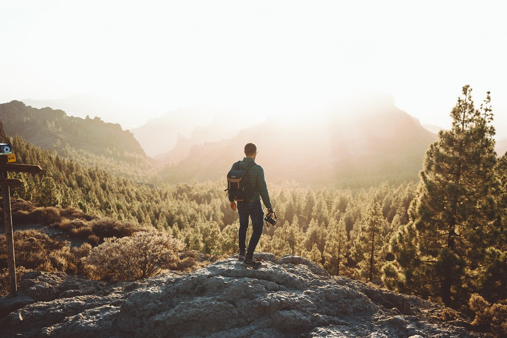 Man holding a camera and observing the horizon.