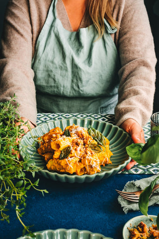 Woman serving creamy pumpkin rigatoni.