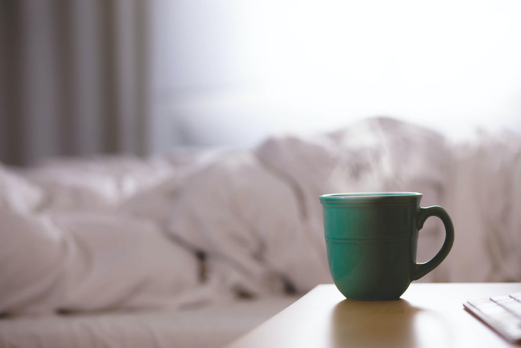 Steaming coffee mug on a bedside table.