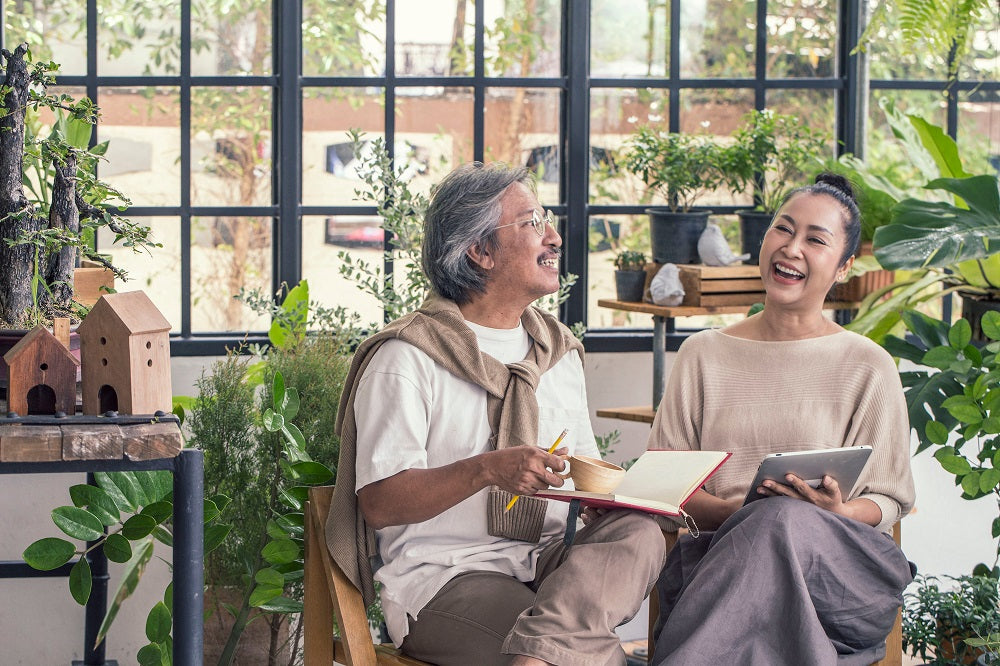 Couple talking to each other with houseplants in the background.