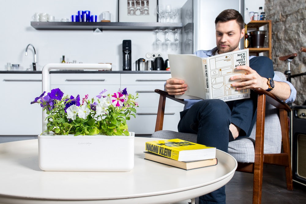 Man reading a book and relaxing next to the Smart Garden 3