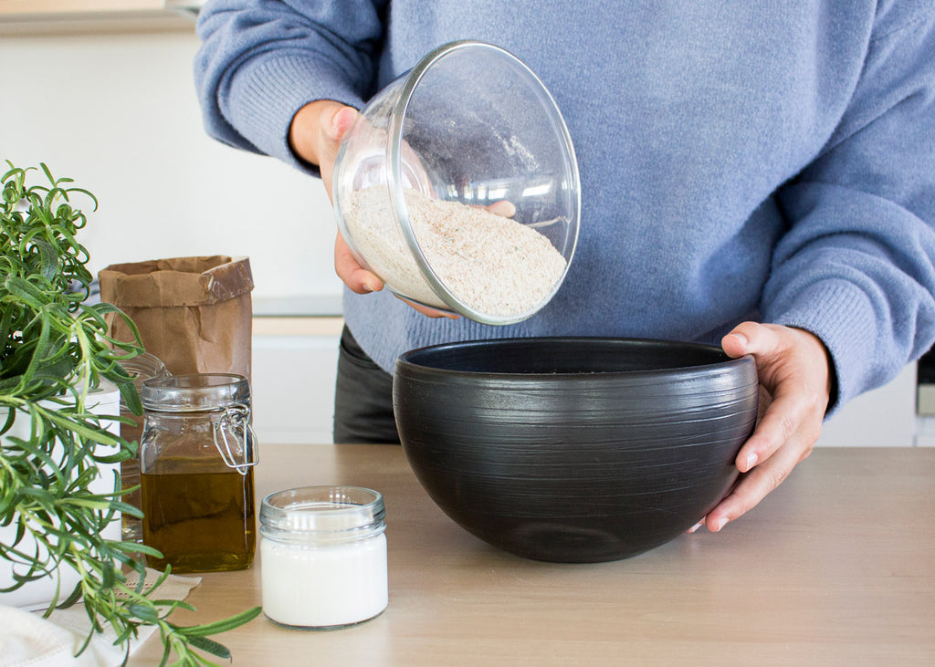 Woman adding sugar to a baking mixture.